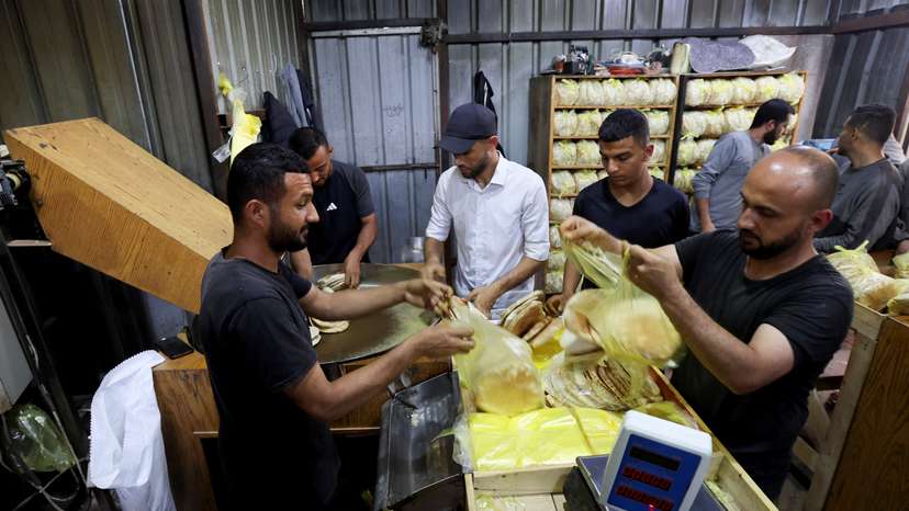Palestinian workers pack bread in a bakery that returned to operation after being closed due to a flour shortage, in Deir Al-Balah