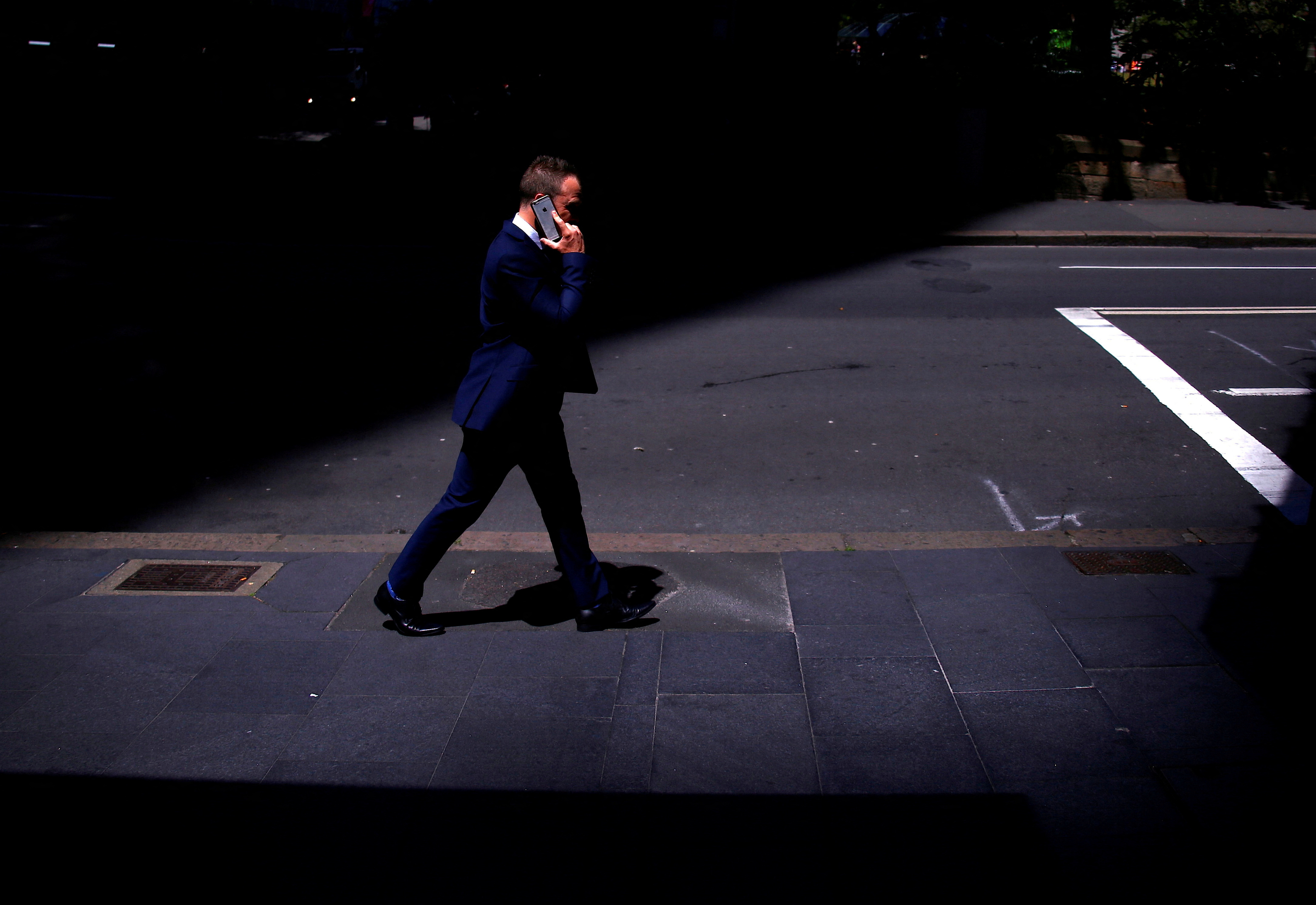 FILE PHOTO: A businessman talks on his Apple iPhone as he walks along a street in the central business district of Sydney