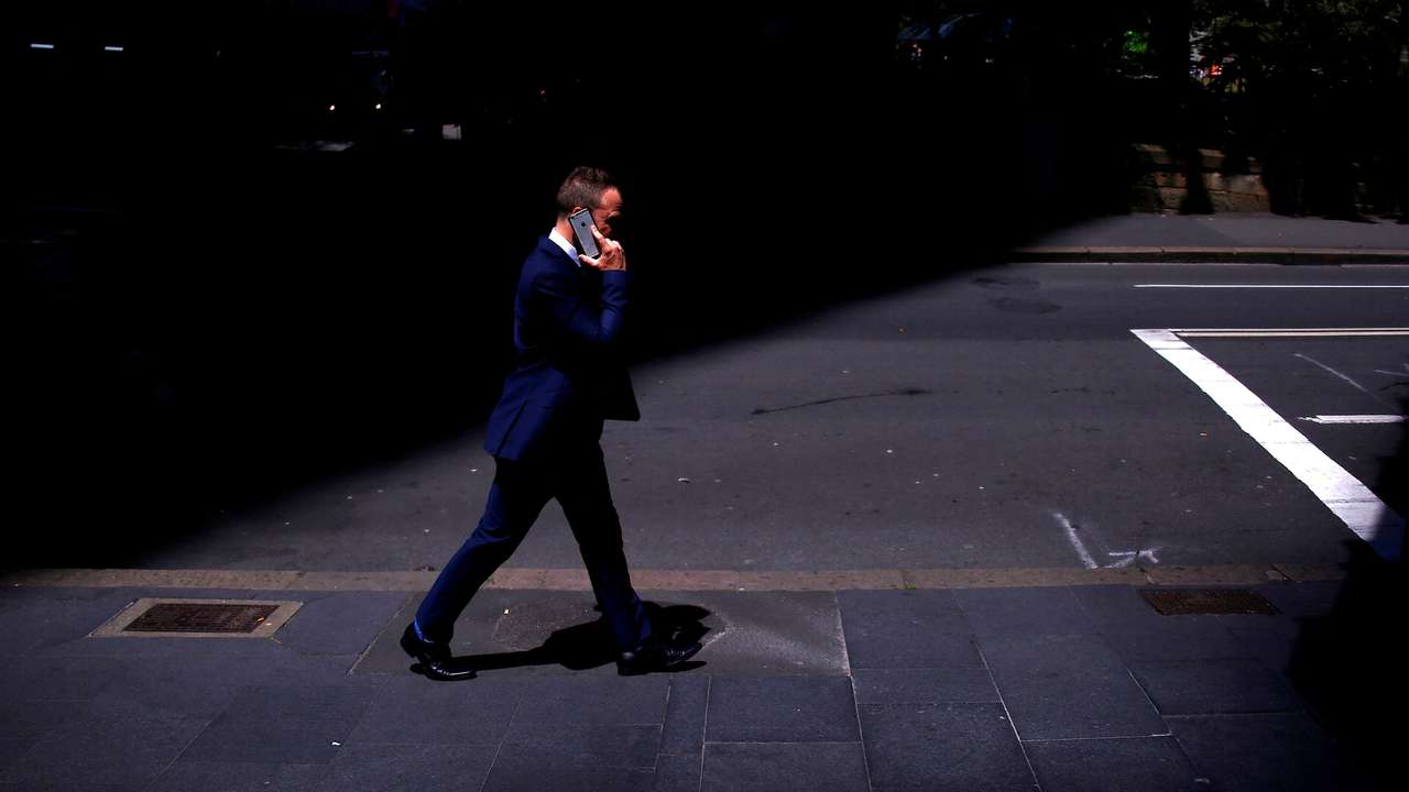 FILE PHOTO: A businessman talks on his Apple iPhone as he walks along a street in the central business district of Sydney