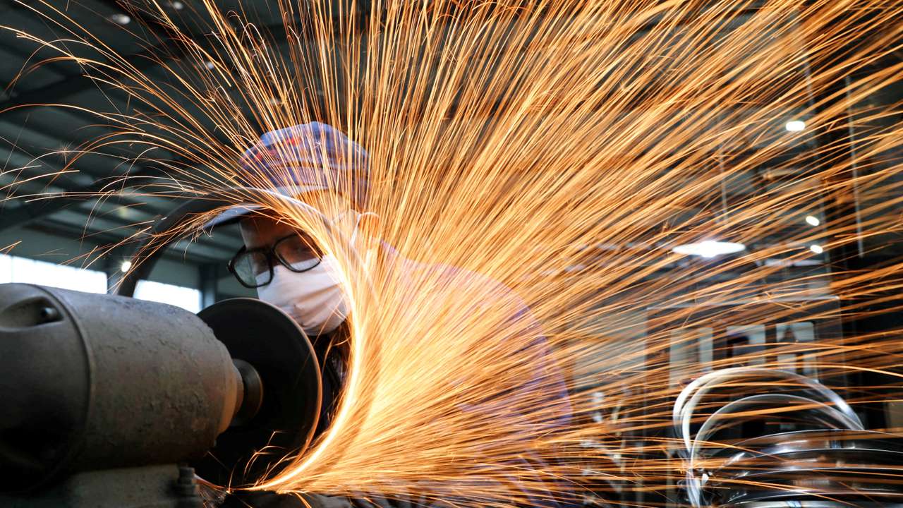 FILE PHOTO: Worker wearing a face mask works on a production line manufacturing bicycle steel rim at a factory in Hangzhou, Zhejiang