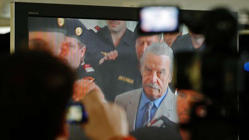 Journalists watch TV screen inside media tent as 73-year-old Austrian Fritzl appears in court on fourth day of his trial in St. Poelten