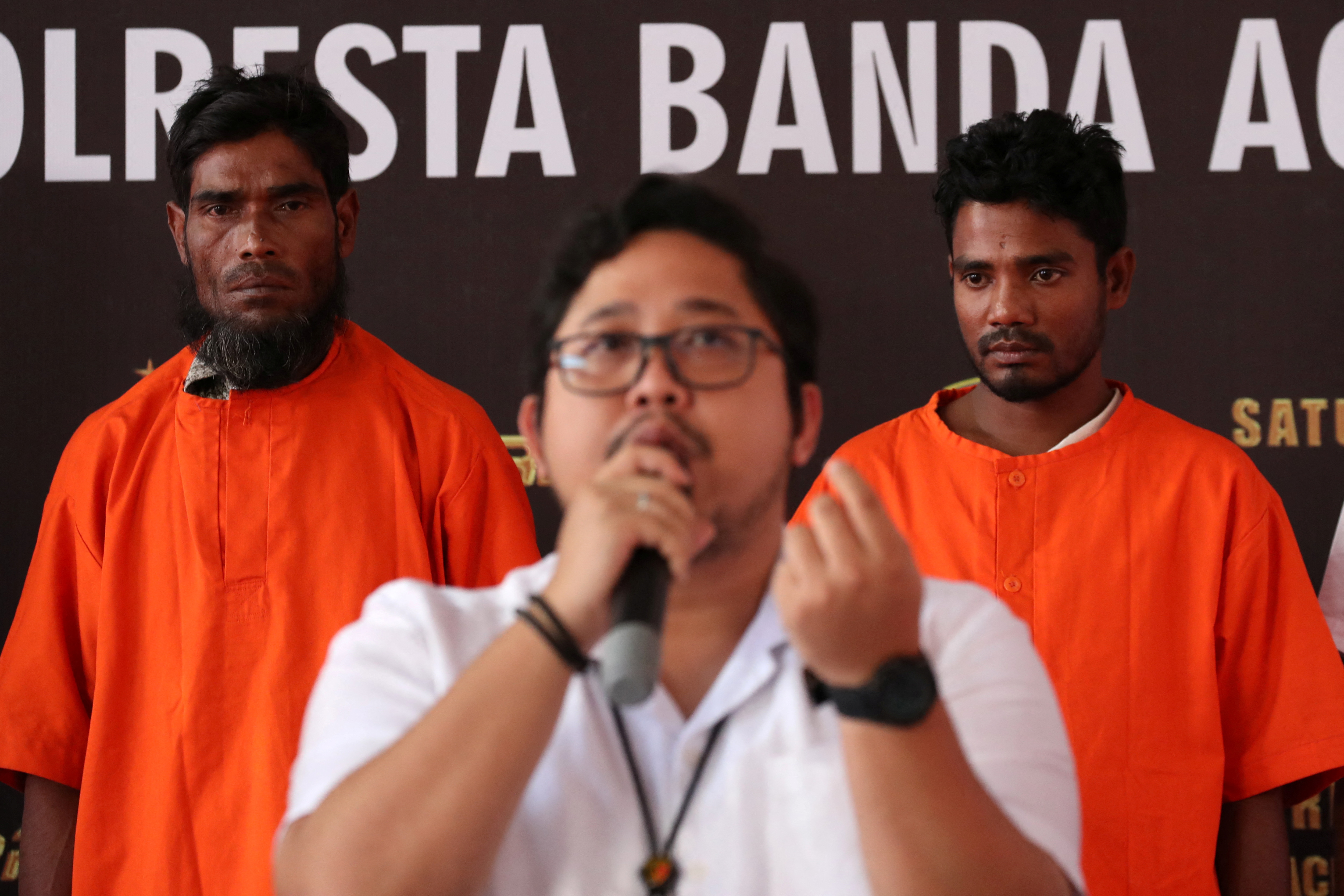 Two suspects, a Bangladesh national and a Rohingya, stand at a police office in Banda Aceh