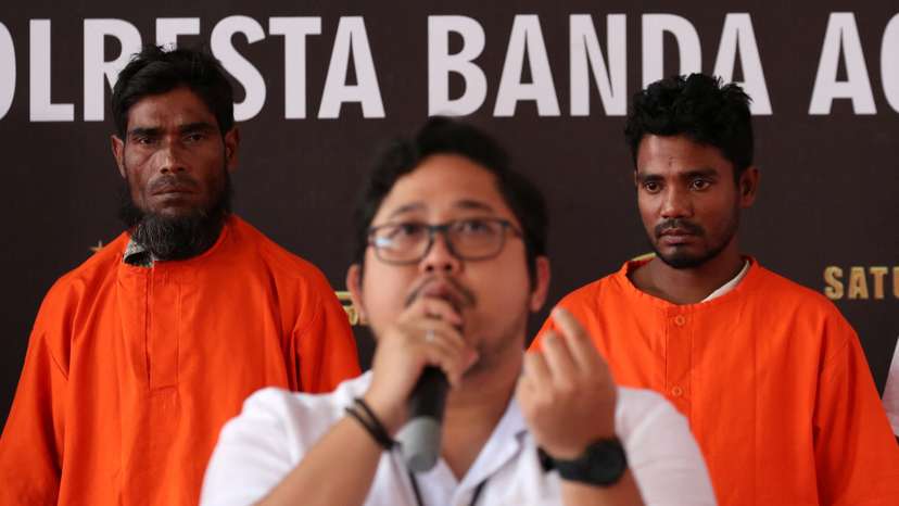 Two suspects, a Bangladesh national and a Rohingya, stand at a police office in Banda Aceh