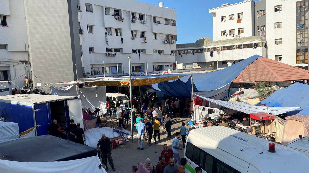 People, including Palestinian children, who fled their house due to Israeli strikes, gather at Al Shifa hospital where they shelter