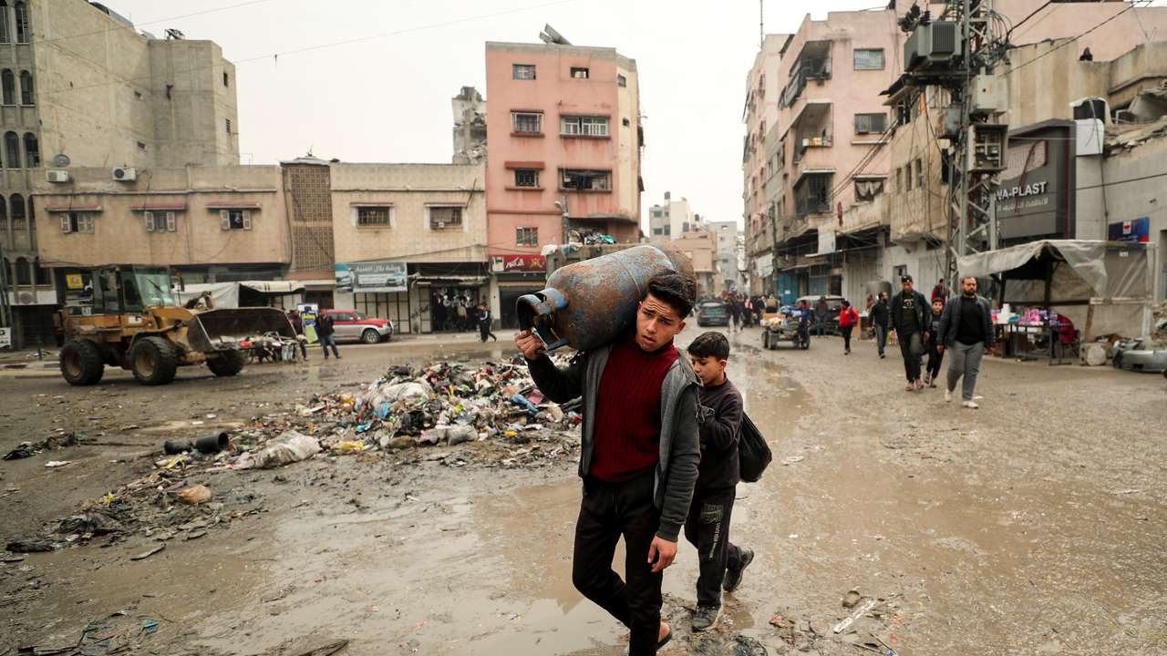 Palestinian carries a cooking gas cylinder, in Gaza City