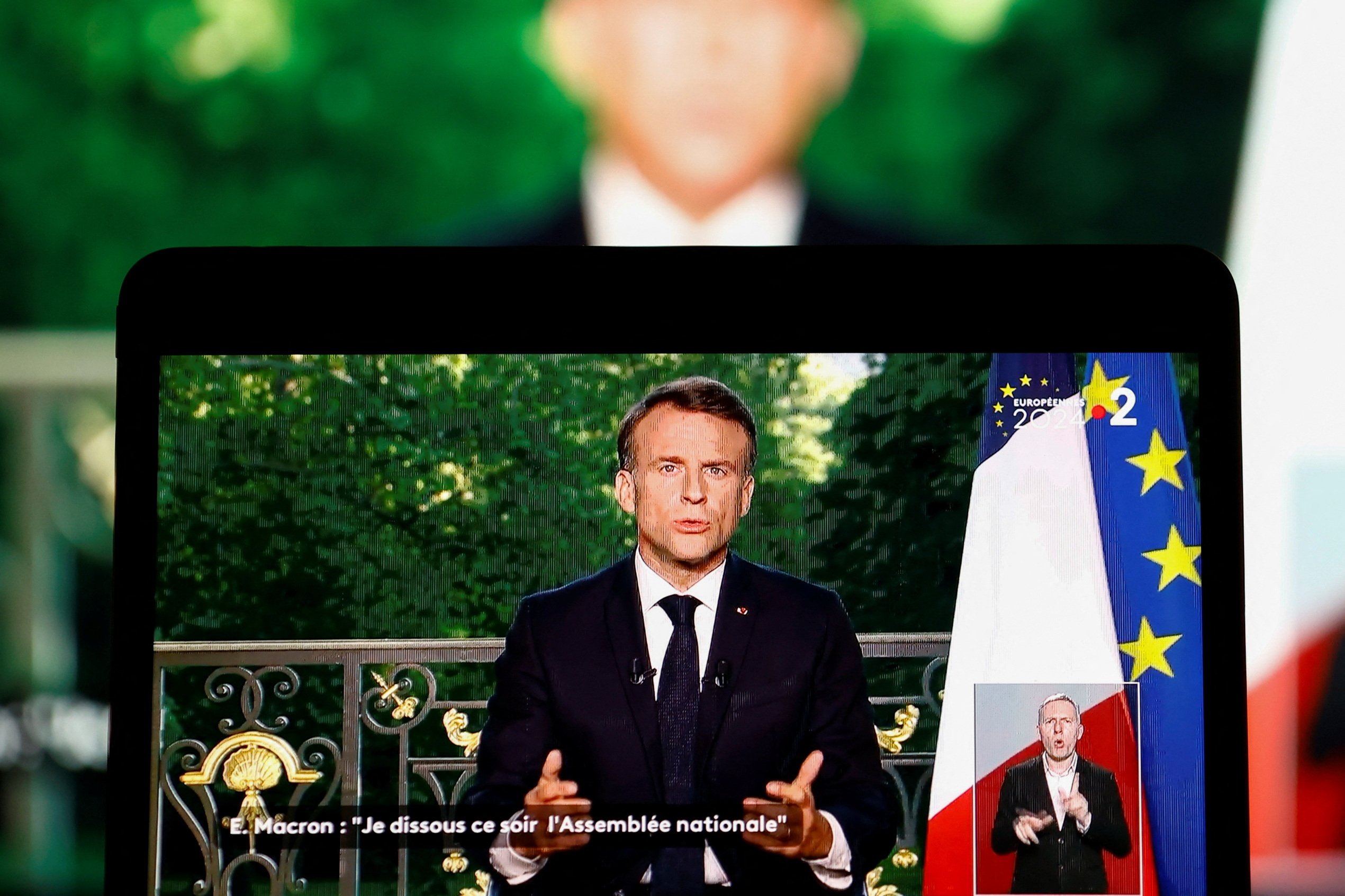 French President Emmanuel Macron appears on a screen as he delivers a speech following results after the polls closed in the European Parliament elections