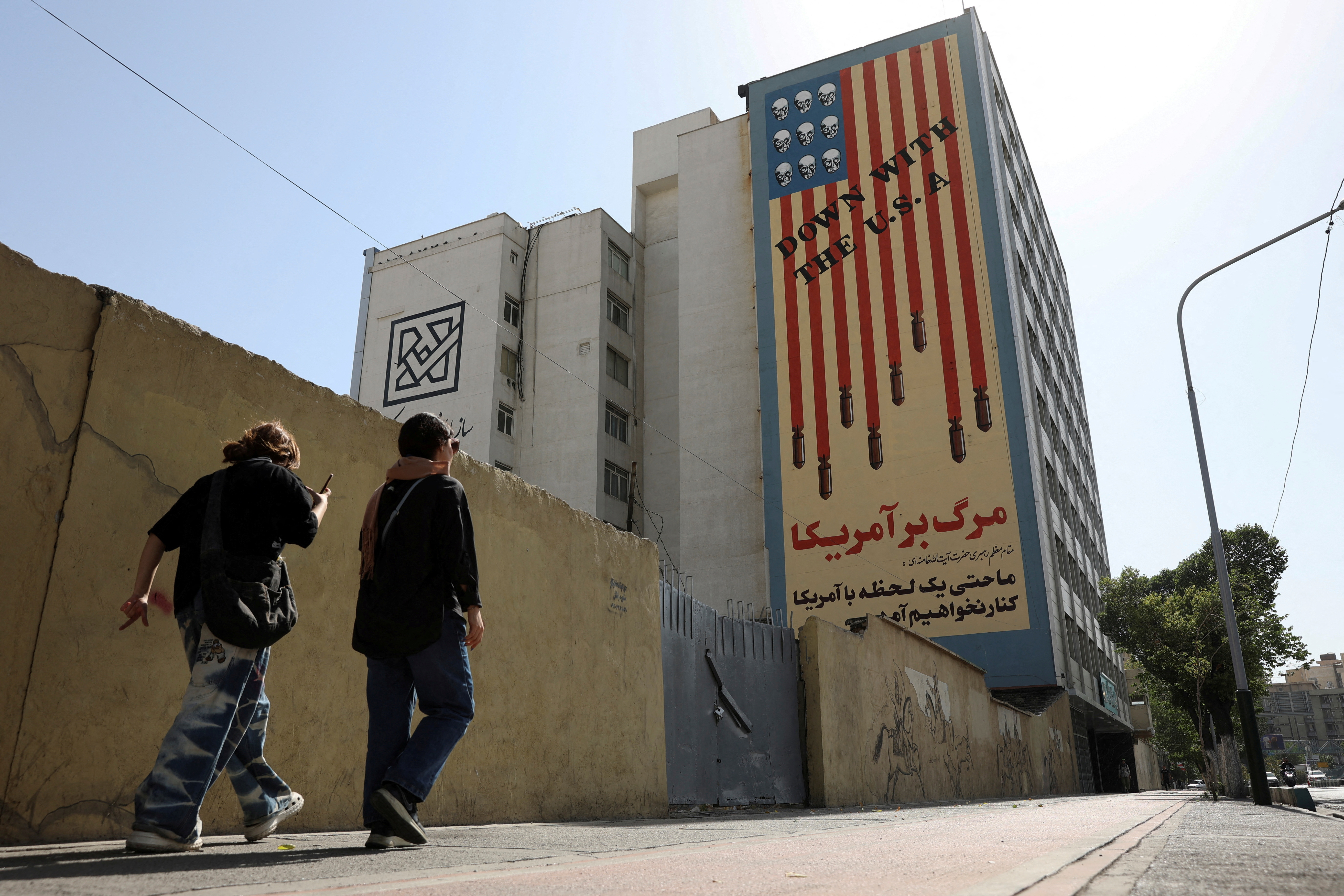 FILE PHOTO: People walk past an anti-US mural on a street in Tehran