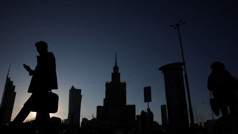 Silhouettes of people walking are seen in front of the communist-era Palace of Culture and Science in centre in Warsaw