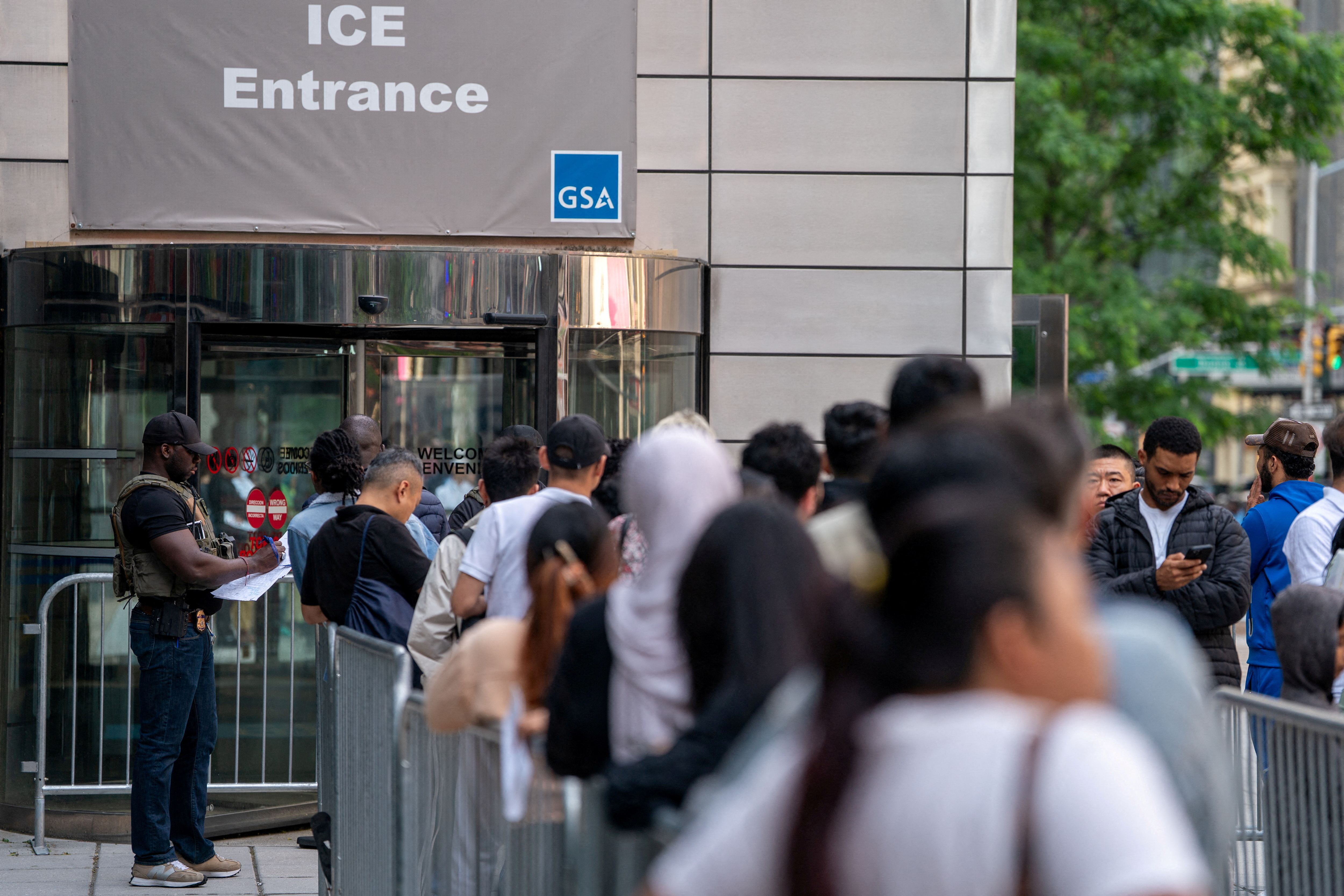 FILE PHOTO: An ICE agent speaks to people lined up to enter the U.S. Immigration Court, in Manhattan