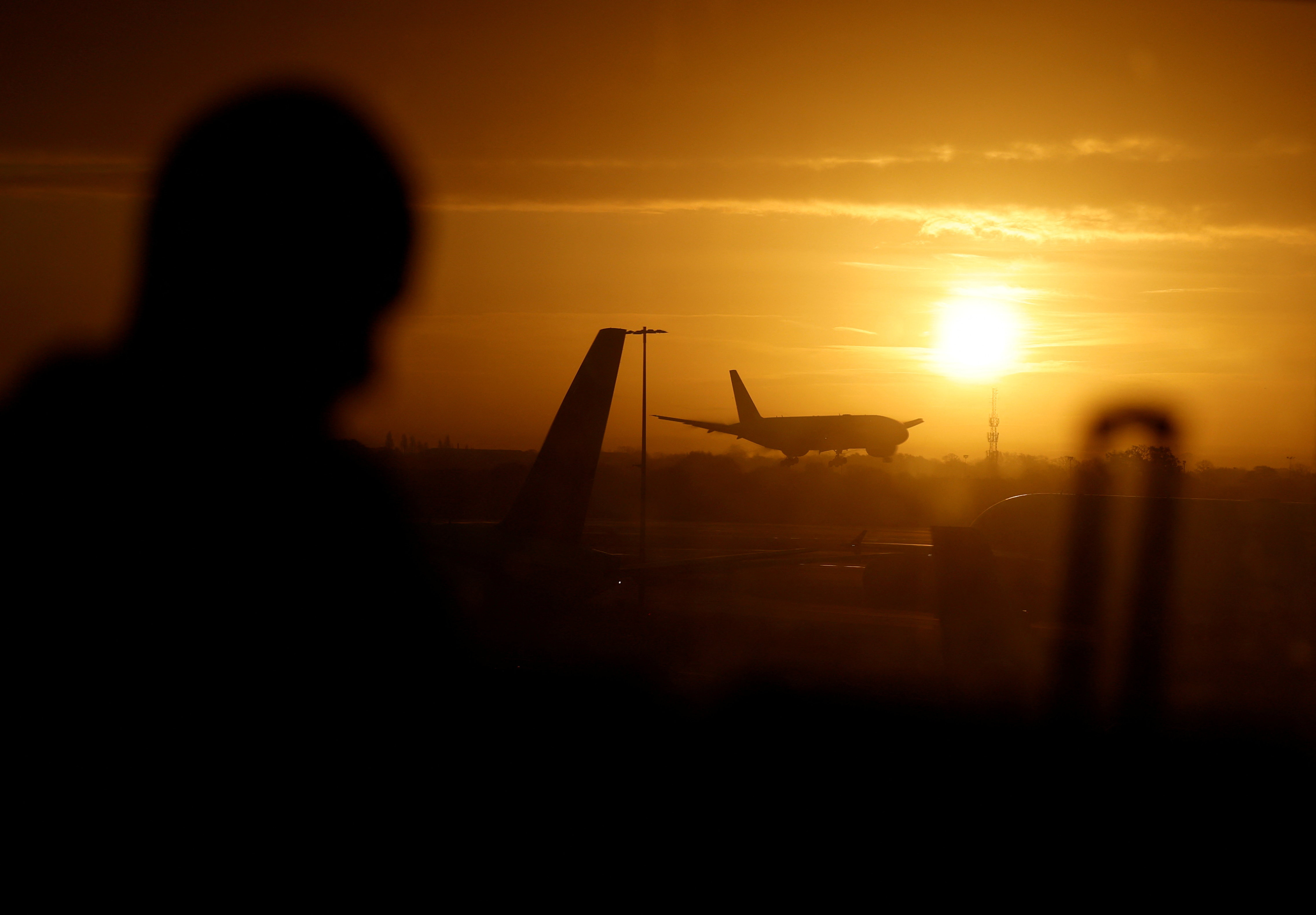 A passenger waits in departures as a British Airways plane lands at London Heathrow airport