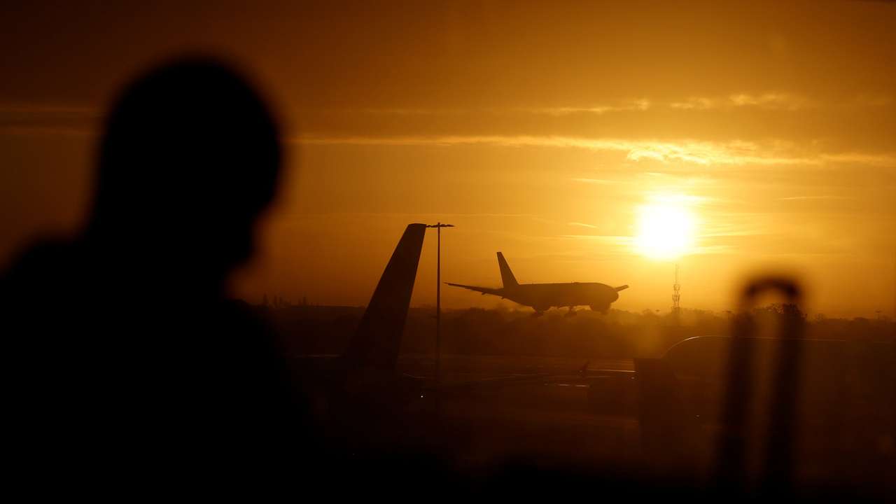 A passenger waits in departures as a British Airways plane lands at London Heathrow airport