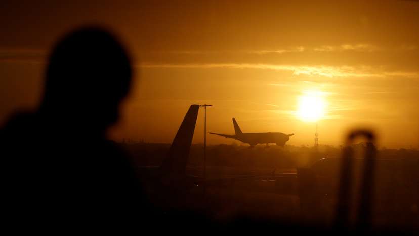 A passenger waits in departures as a British Airways plane lands at London Heathrow airport