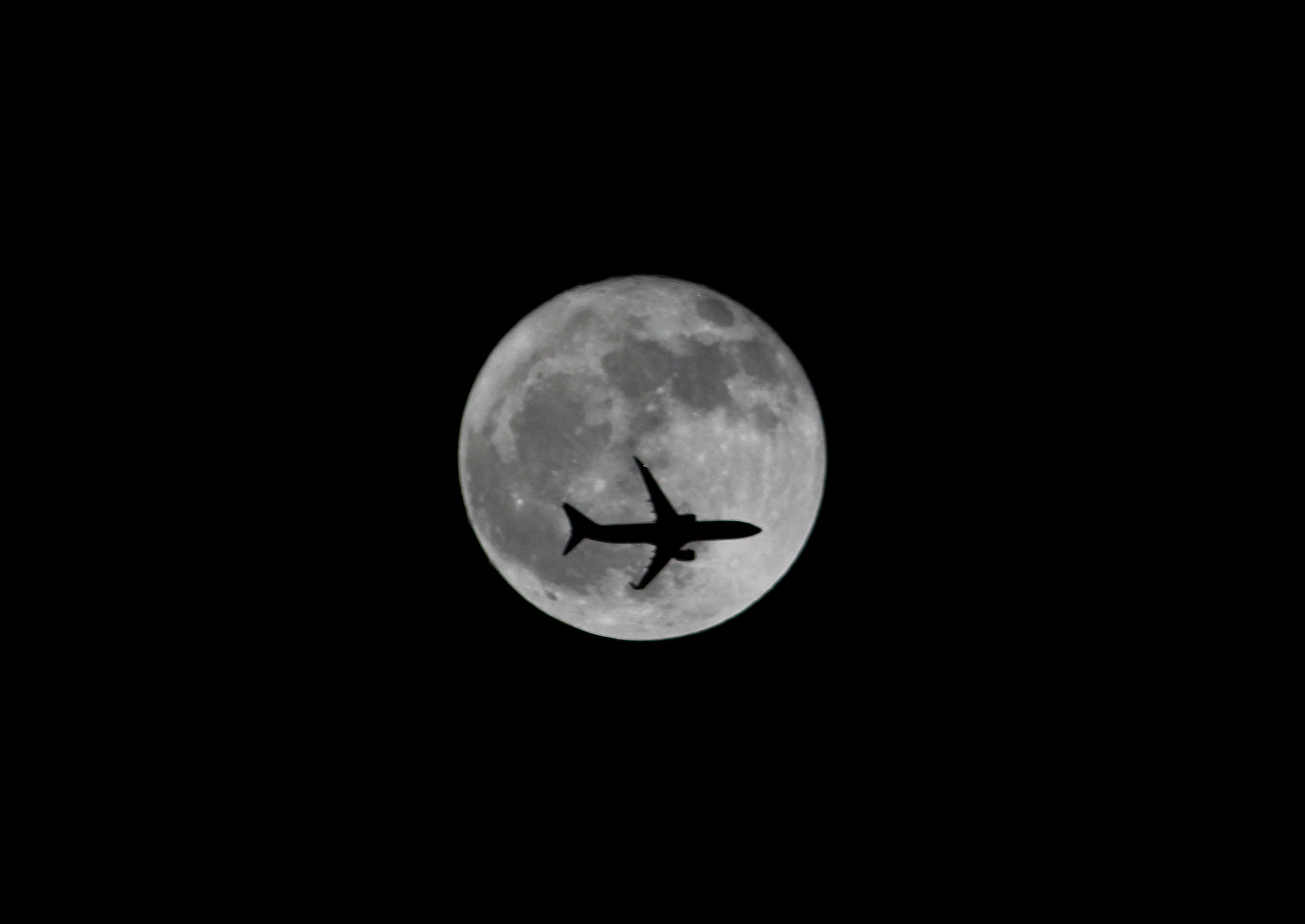 FILE PHOTO: Passenger plane passes the moon as it comes into land at the international airport in Chennai