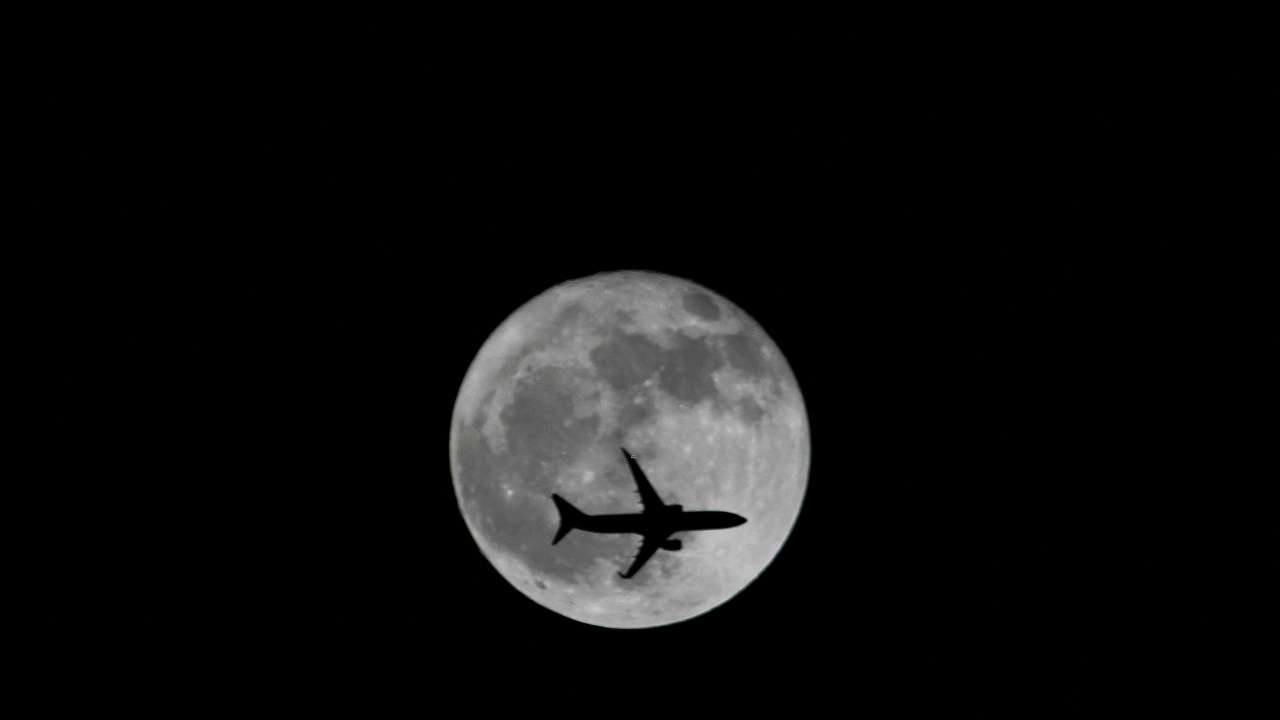 FILE PHOTO: Passenger plane passes the moon as it comes into land at the international airport in Chennai