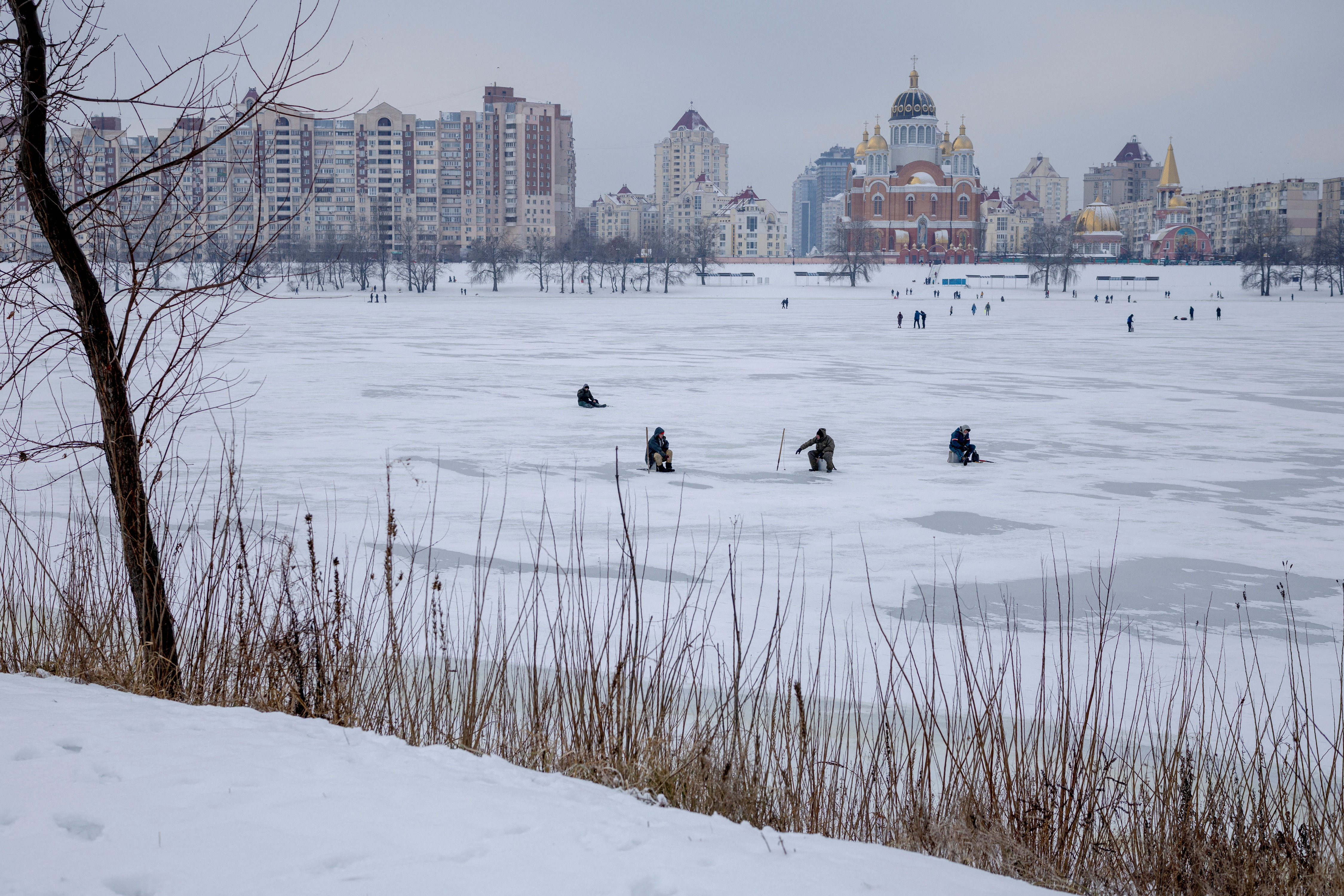 Men fish in a frozen lake, amid Russia's attack on Ukraine, on a cold winter day in Kyiv