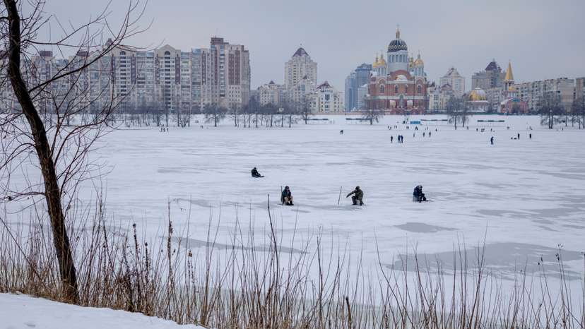 Men fish in a frozen lake, amid Russia's attack on Ukraine, on a cold winter day in Kyiv