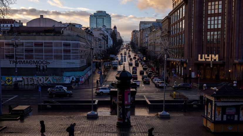 People walk along Khreshchatyk street as the evening sun breaks through the clouds after a rainy day in Kyiv