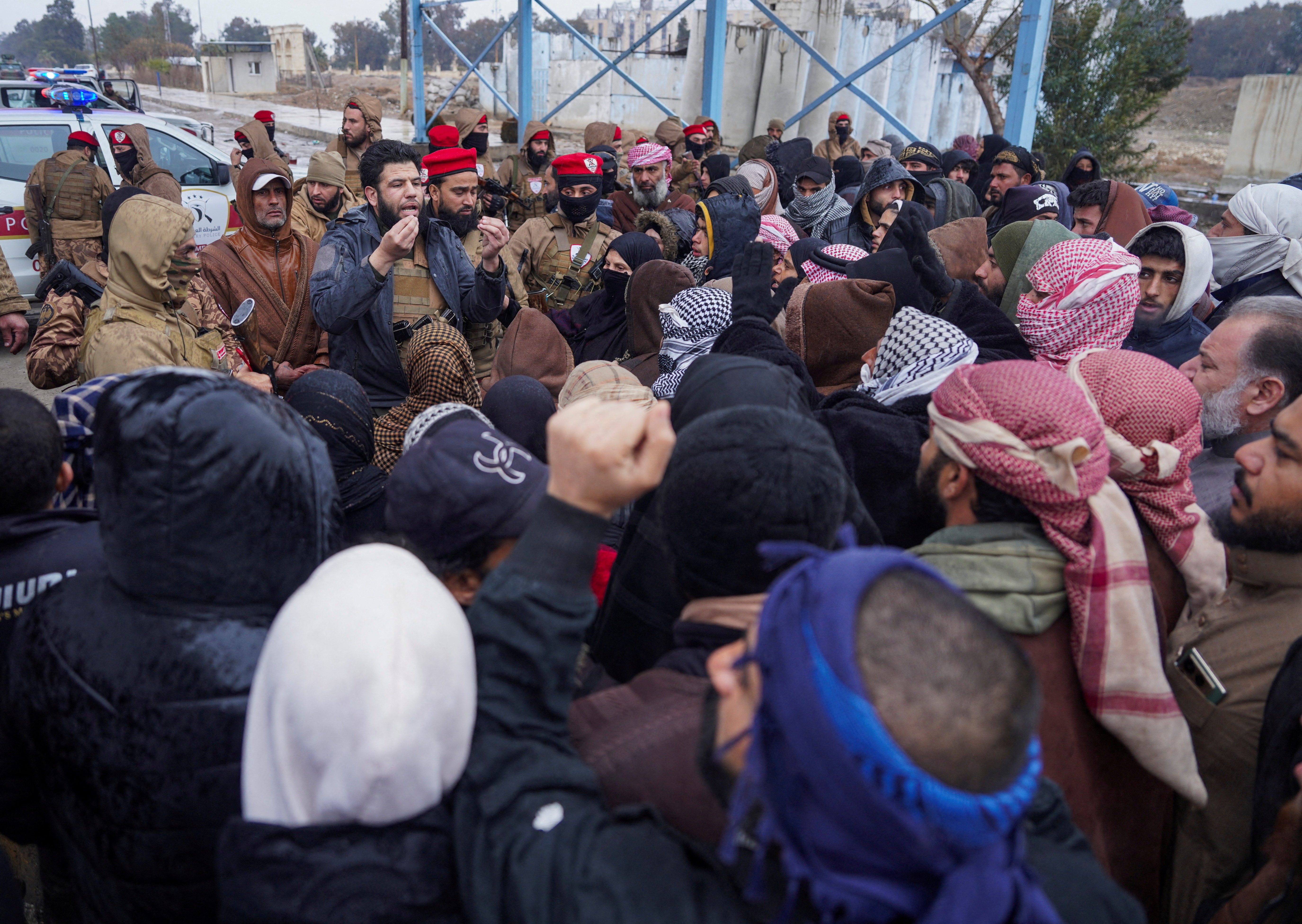 FILE PHOTO: A member of Syrian military police speaks to relatives of detainees of al-Aqtan prison, where Islamic State detainees are held, after the Syrian government took control of the facility, in Raqqa
