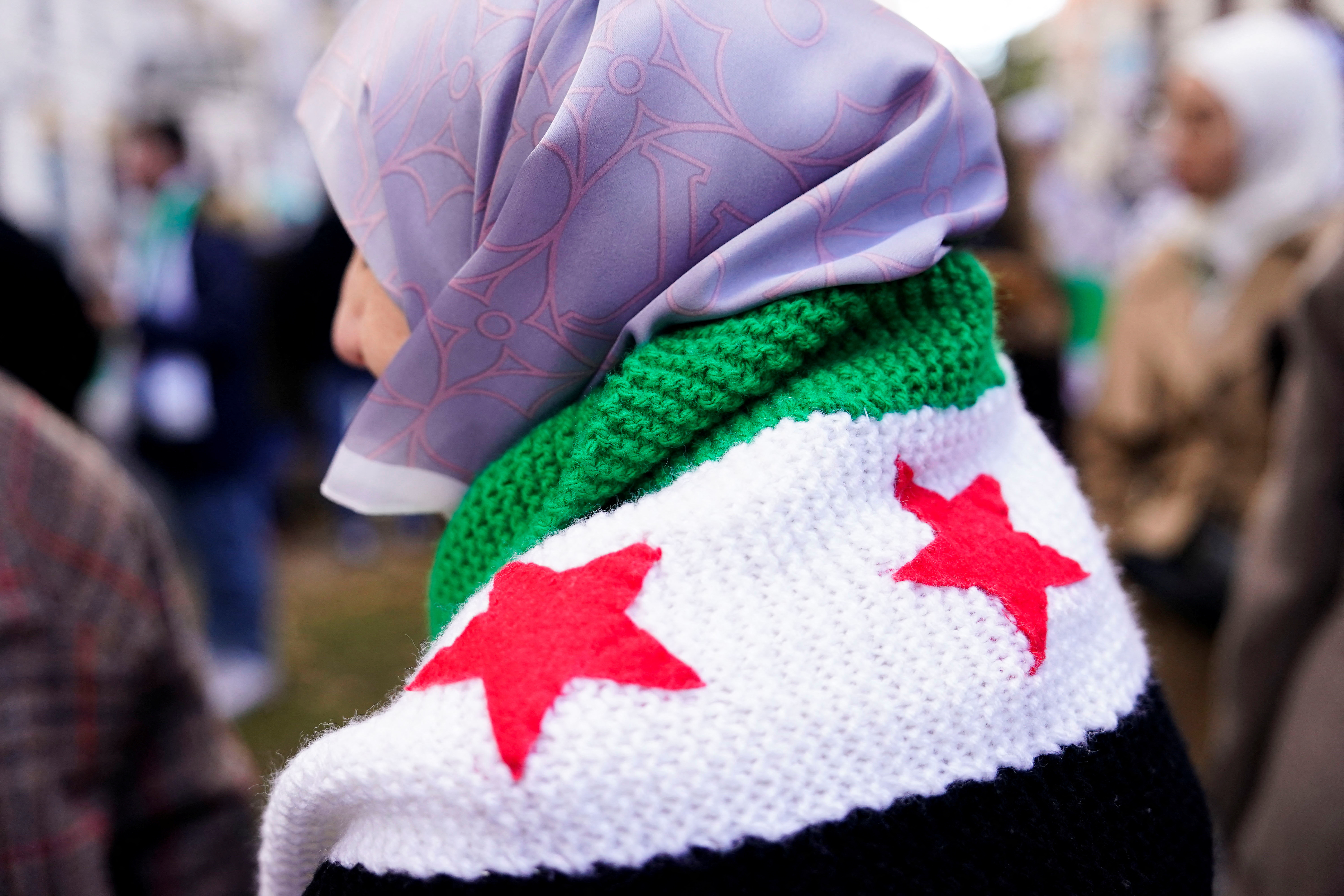 A person wears a crocheted Syrian opposition flag during a demonstration celebrating the fall of Bashar Al-Assad regime outside the Syrian embassy in Madrid