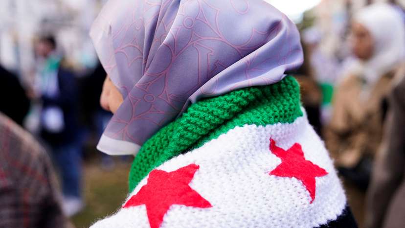 A person wears a crocheted Syrian opposition flag during a demonstration celebrating the fall of Bashar Al-Assad regime outside the Syrian embassy in Madrid