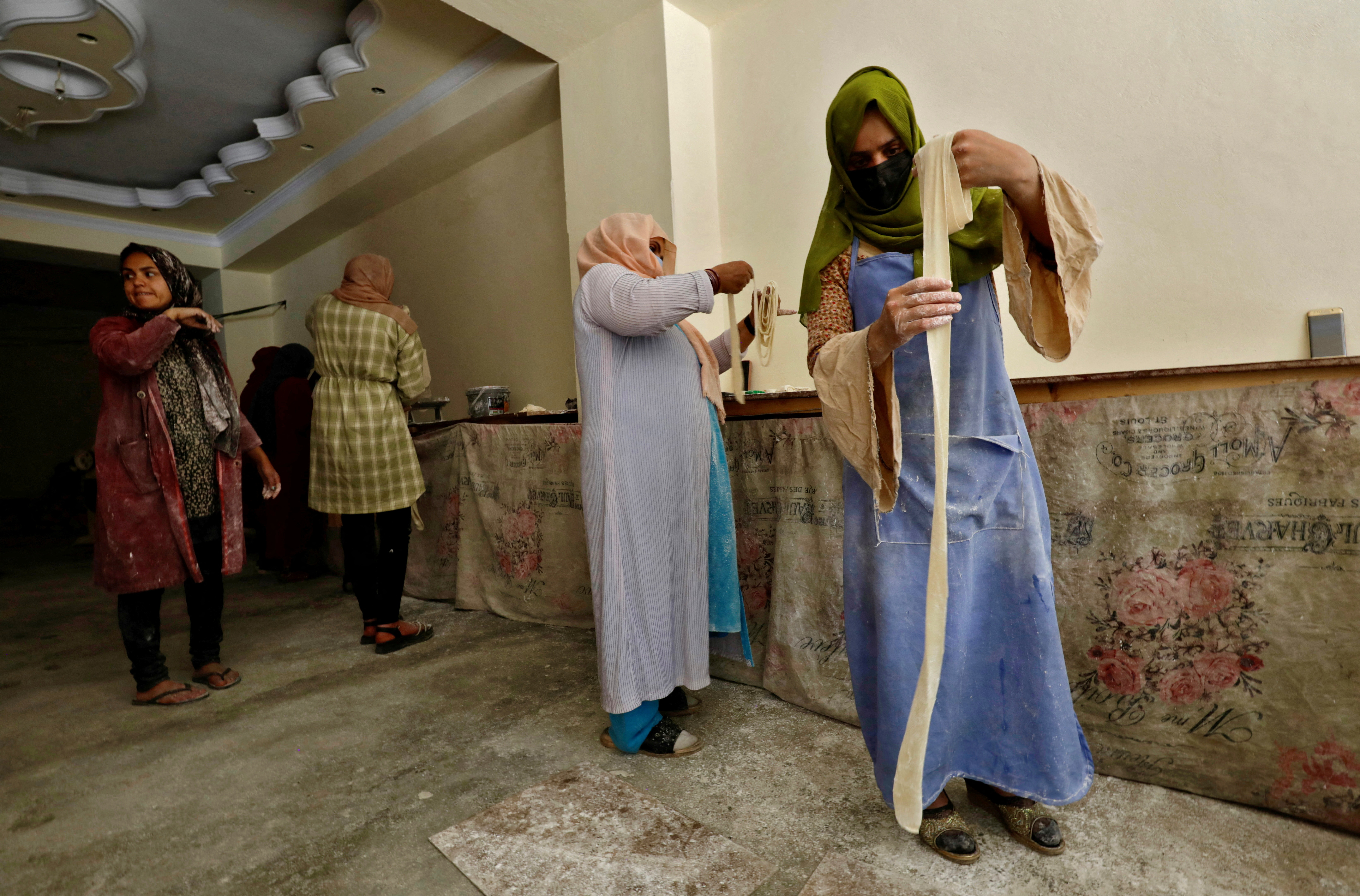 FILE PHOTO: Afghan women prepare dough to make traditional cookies inside a bakery, in Kabul