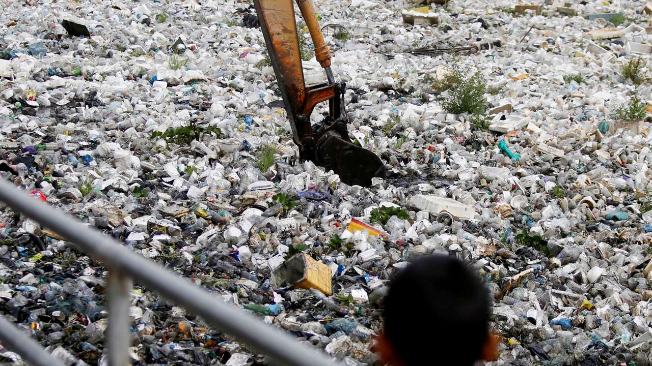 FILE PHOTO: A child watches as heavy machinery collects rubbish at a sewage canal in Phnom Penh