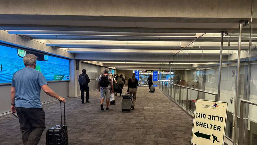 People walk next to a sign directing for Shelter after landing in Israel at the arrivals section of Ben Gurion International airport in Lod near Tel Aviv