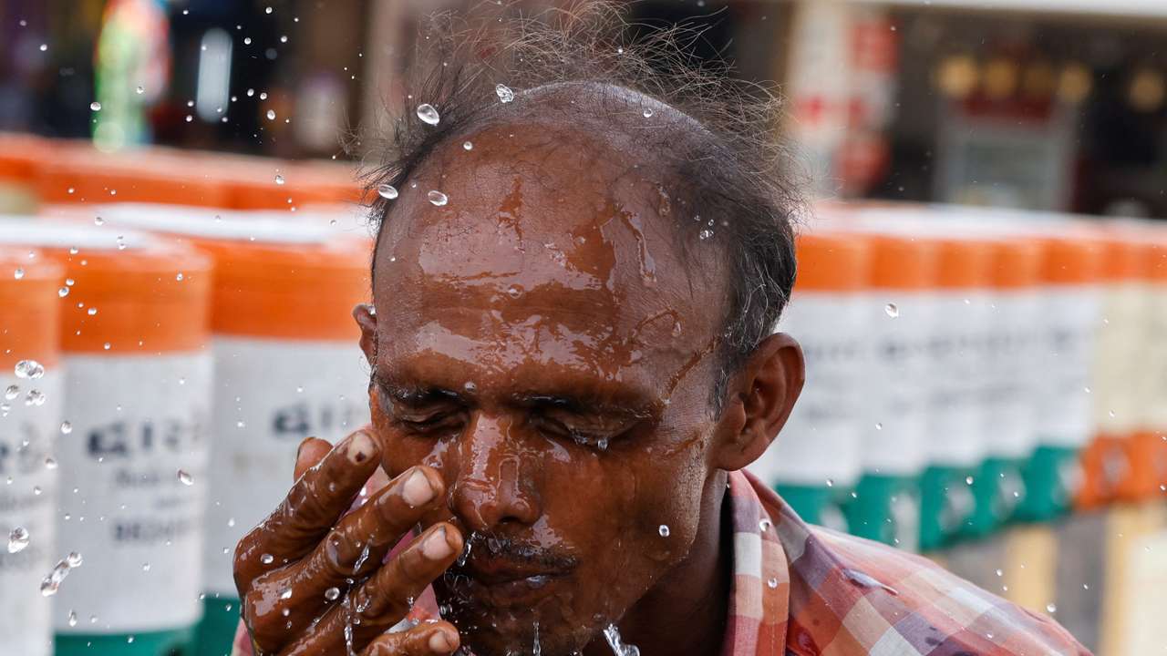 A man sprays cold water on his face from a water jar during a heatwave in Ahmedabad