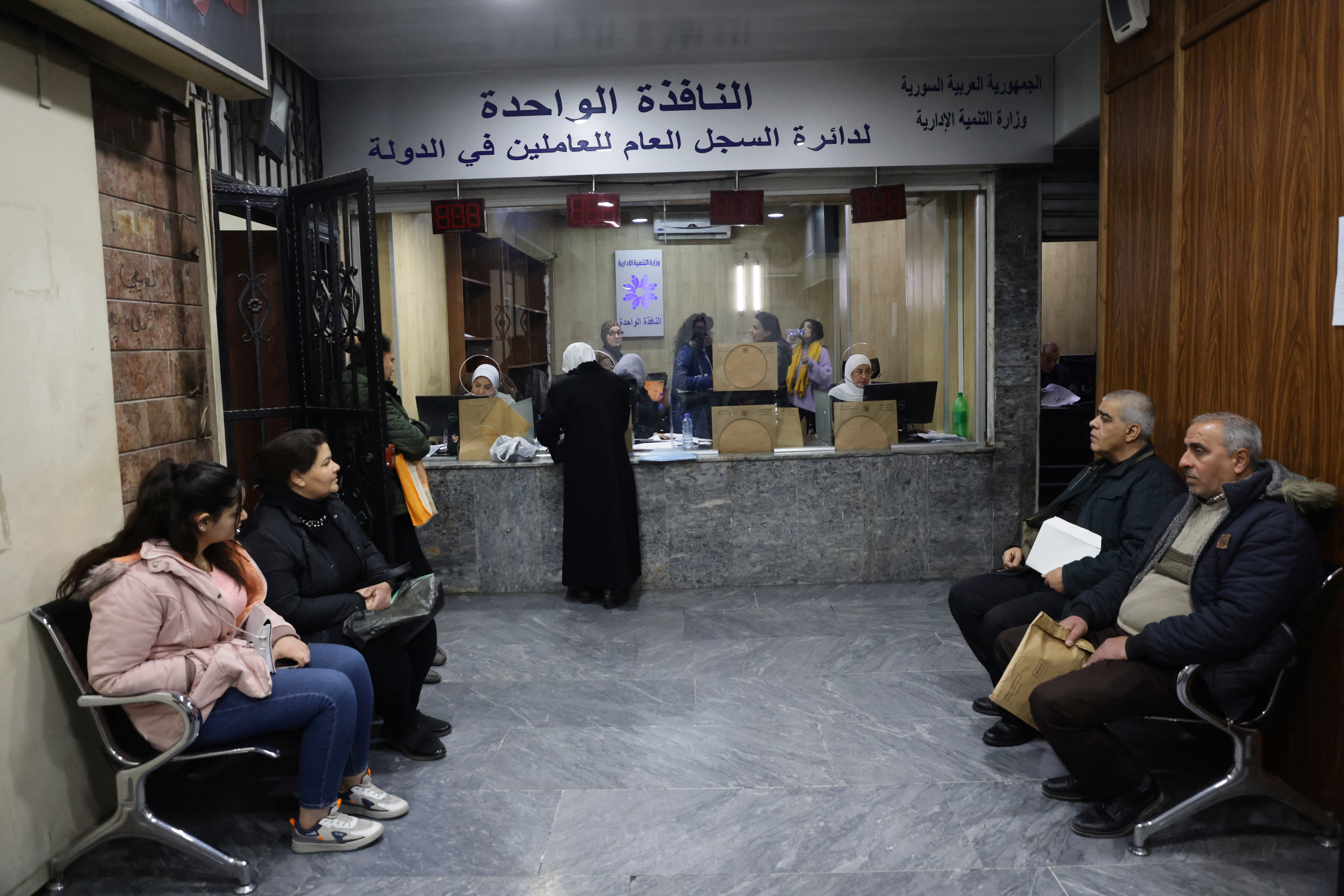 People wait at a government building in Damascus