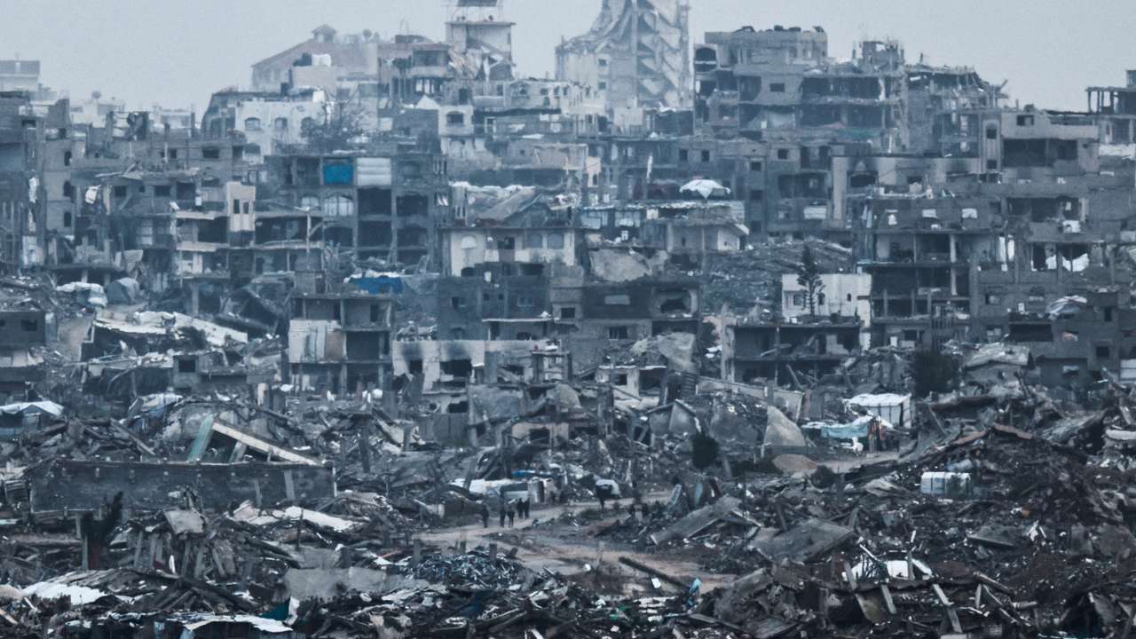 Palestinians walk near damaged buildings in the Gaza Strip , as seen from Israel's border with Gaza, Israel