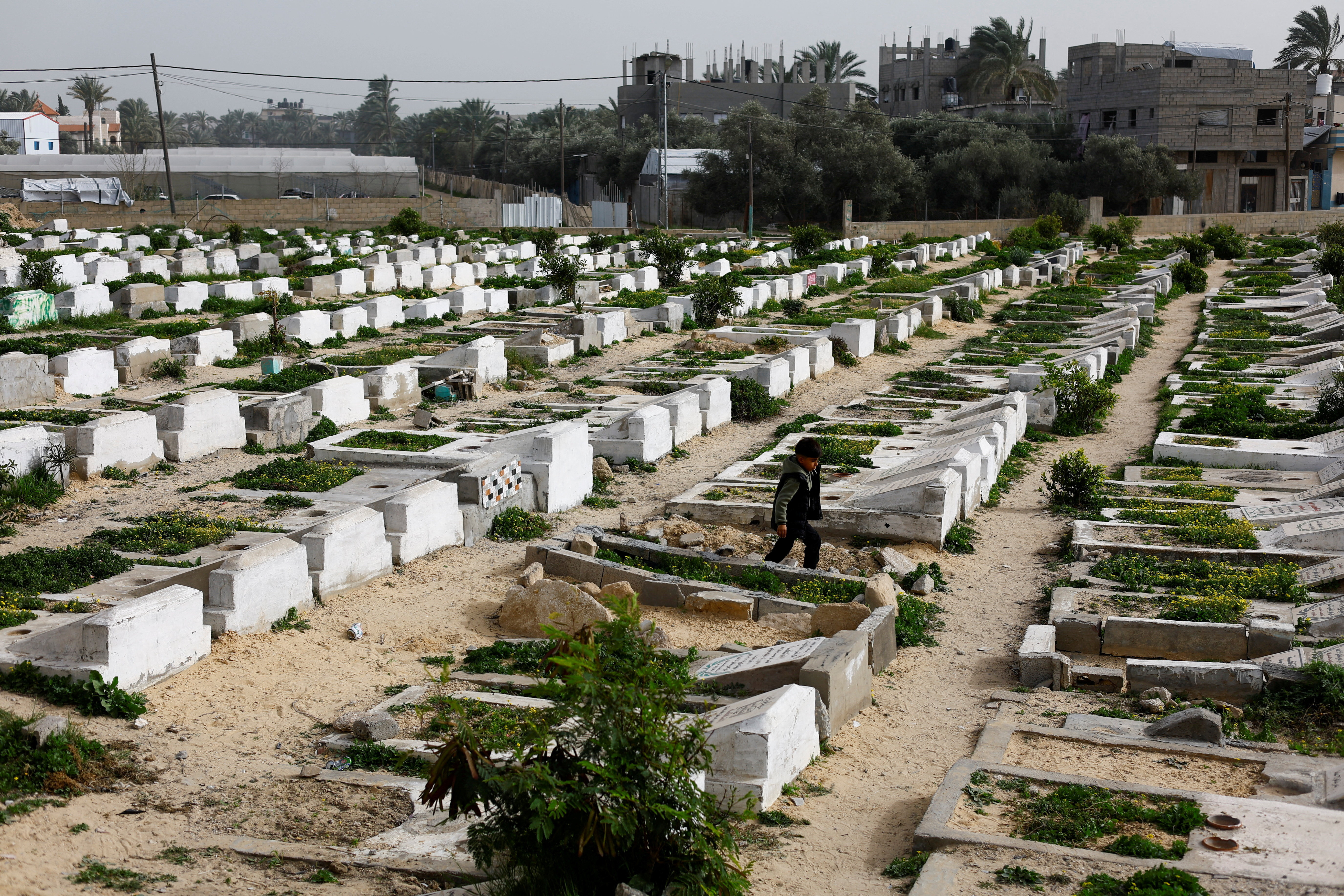 Palestinians visit the cemetery with graves of some of those killed during the war, in Deir al-Balah