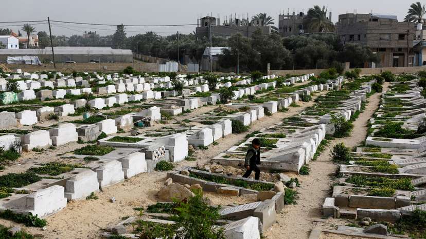 Palestinians visit the cemetery with graves of some of those killed during the war, in Deir al-Balah