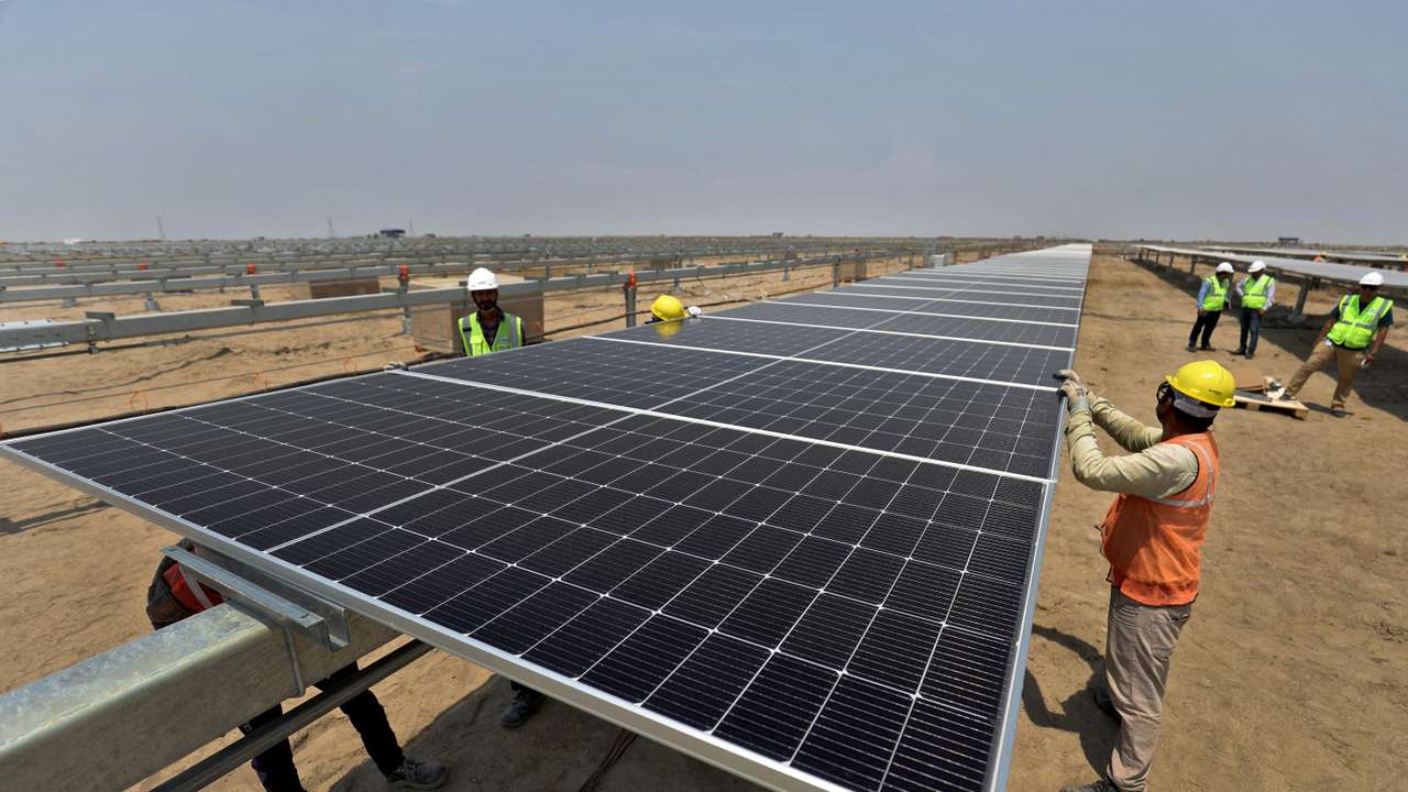 FILE PHOTO: Workers install solar panels at the Khavda Renewable Energy Park of Adani Green Energy Ltd (AGEL) in Khavda