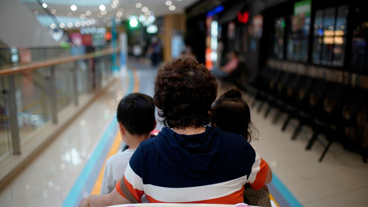 Person sits in a toy car with children at a shopping mall in Shanghai