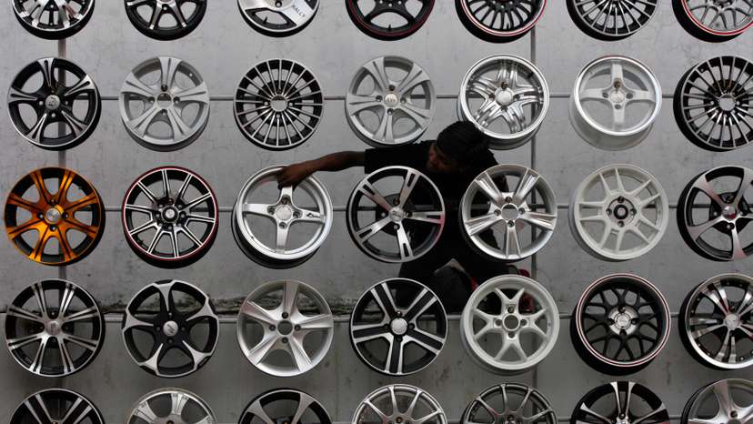 A worker displays alloy wheels for sale outside a car accessories shop in the southern Indian city of Hyderabad