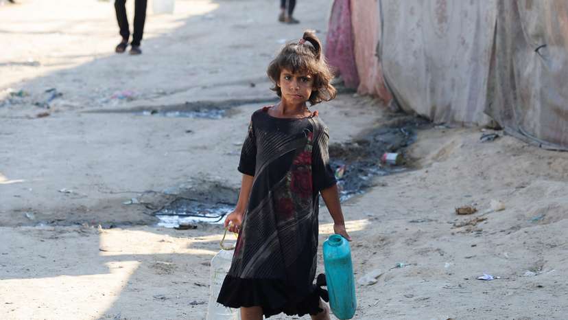 Palestinians carry containers to fill them with water, amid the Israel-Hamas conflict, in Deir Al-Balah
