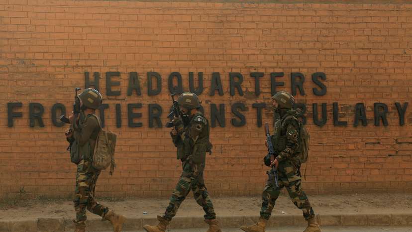 Army soldiers walk, after suicide bombers targeted the headquarters of a Pakistani paramilitary force in Peshawar