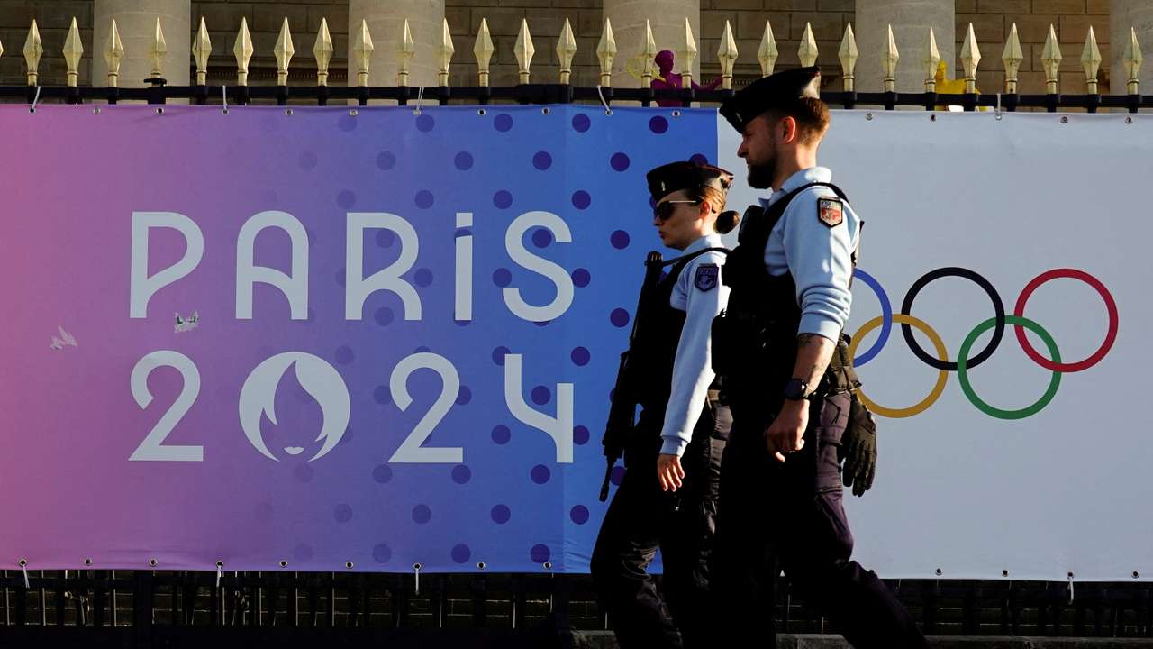 FILE PHOTO: French gendarmes patrol a street near a poster advertising the Paris 2024 Summer Games in Paris