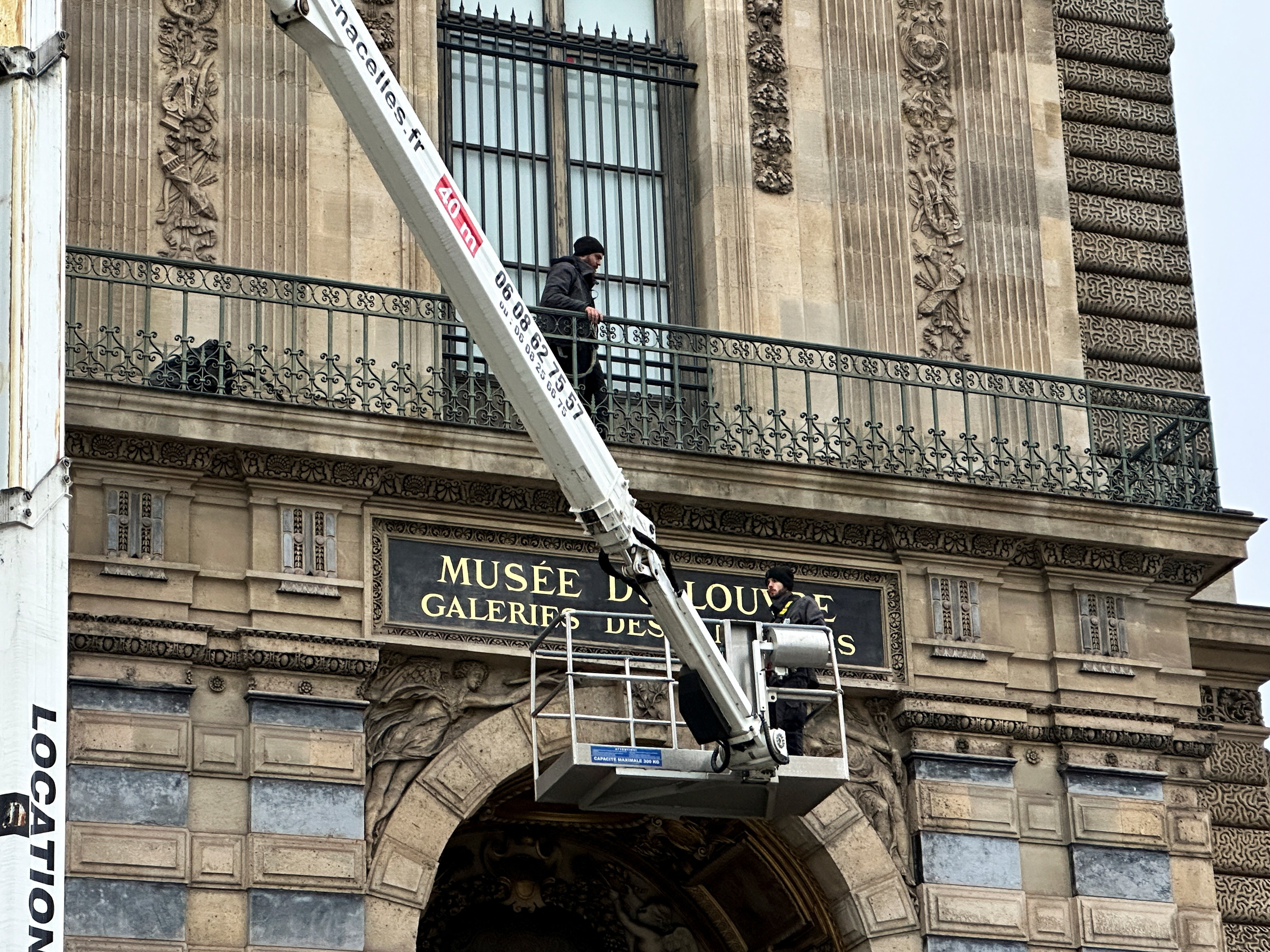 Workers install a security grill at the window of the Louvre museum