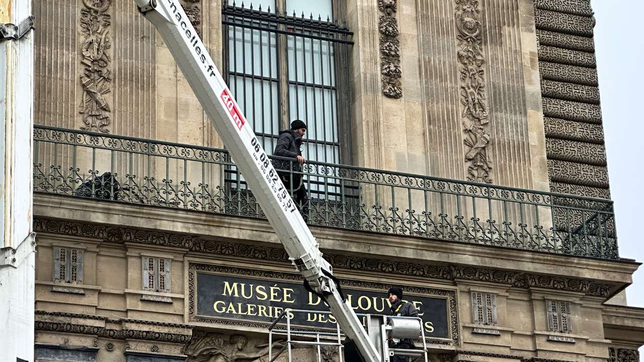 Workers install a security grill at the window of the Louvre museum