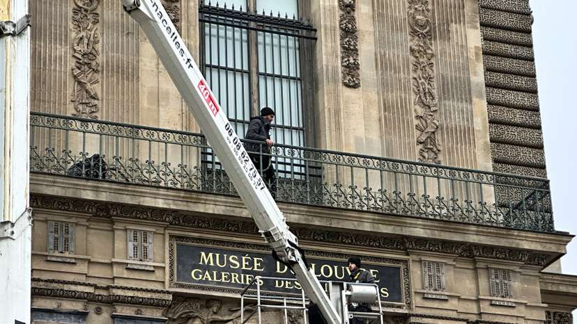 Workers install a security grill at the window of the Louvre museum