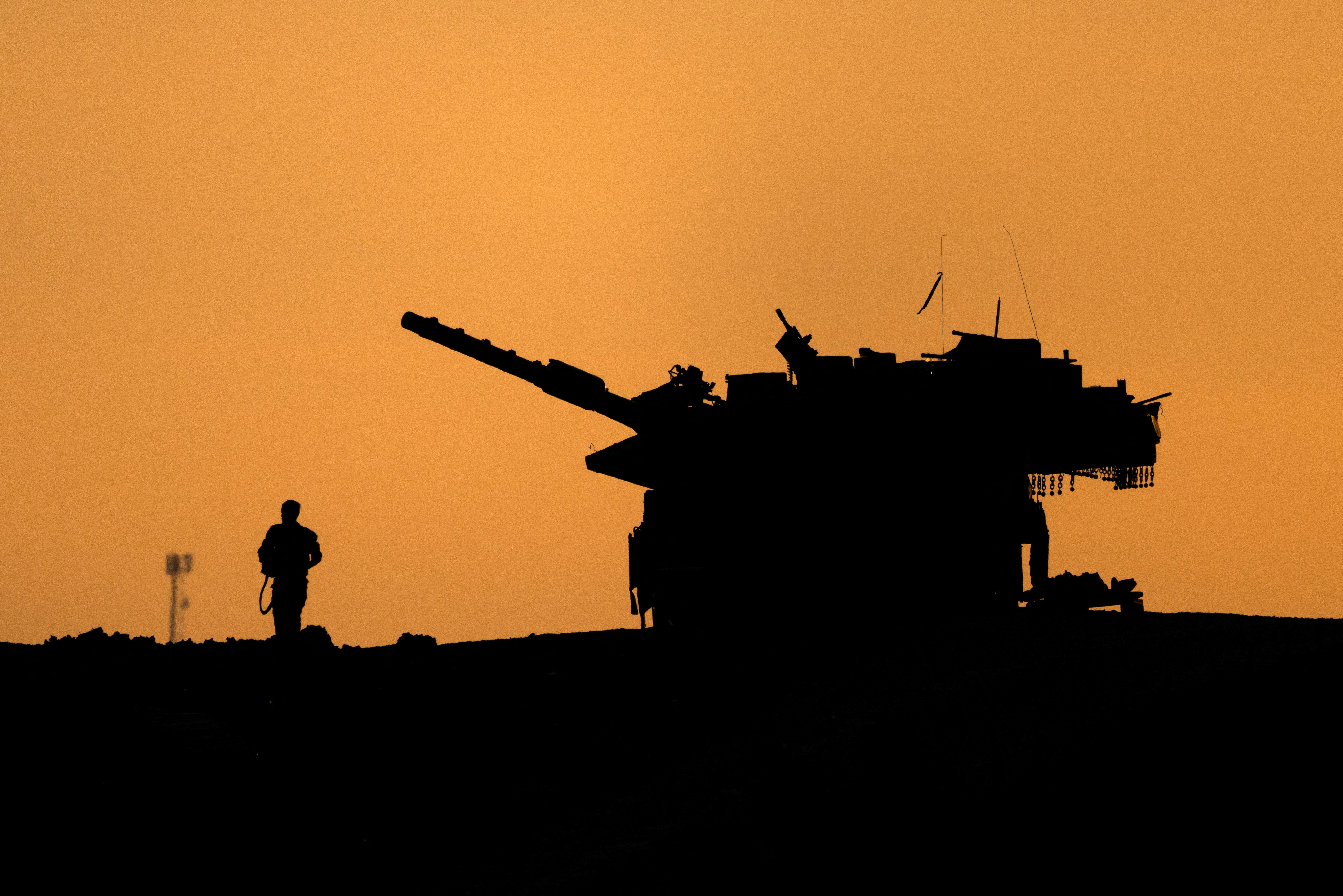 The silhouettes of a military vehicle and a soldier are seen near the Gaza border