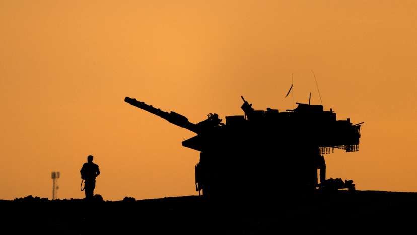 The silhouettes of a military vehicle and a soldier are seen near the Gaza border