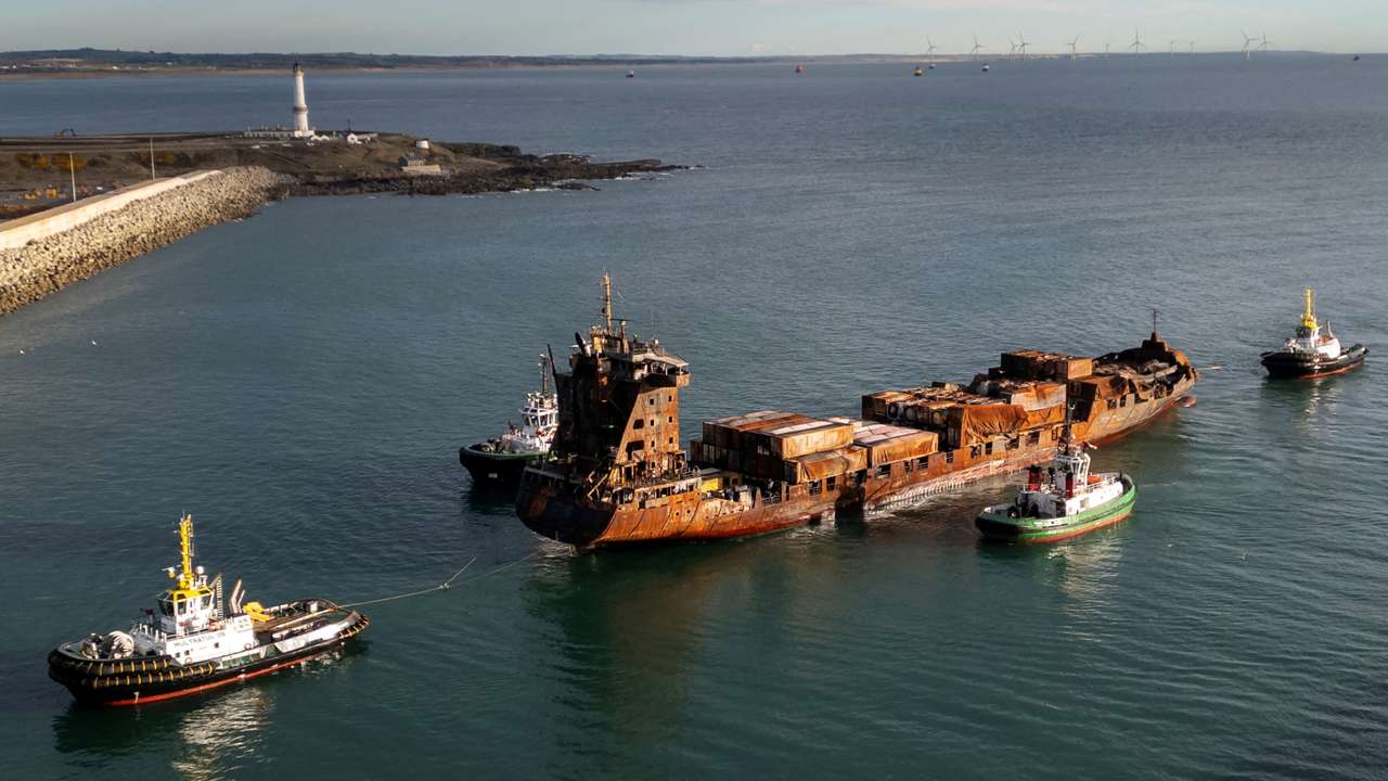 A drone view shows the container ship Solong, damaged as a result of colliding with the anchored Stena Immaculate oil tanker ship, towed by tug boats into the port of Aberdeen