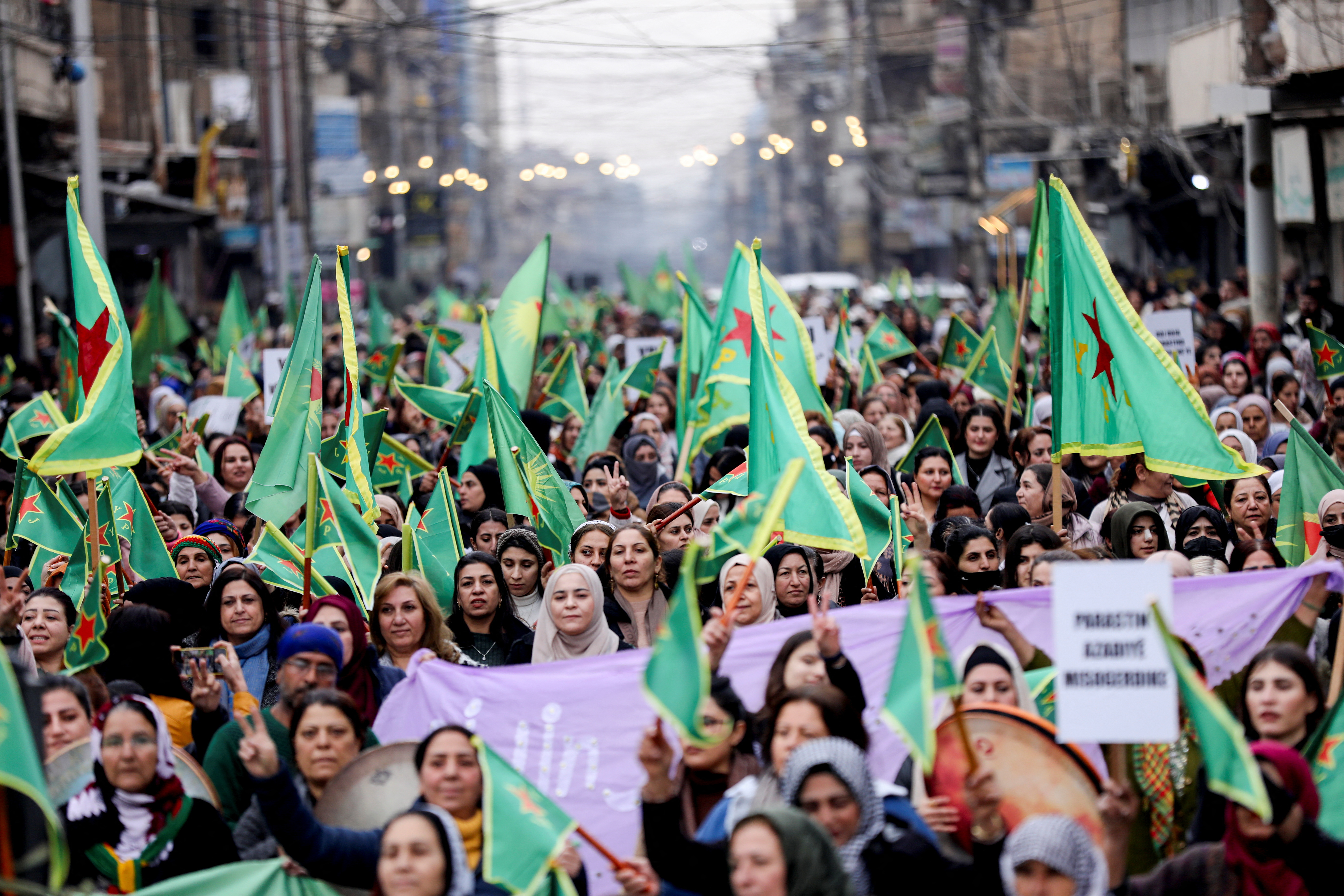 Women hold Women's Protection Units (YPJ) flags during a rally, in Qamishli