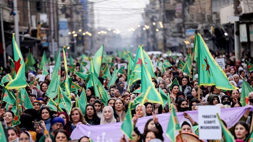 Women hold Women's Protection Units (YPJ) flags during a rally, in Qamishli