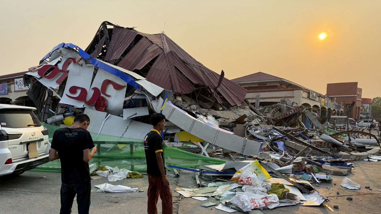 People stand near a commercial facility which collapsed due to an earthquake, in Naypyitaw