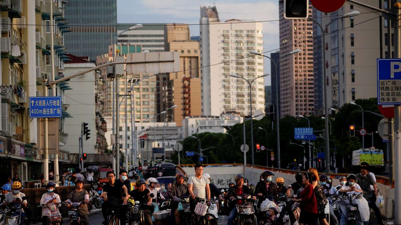 People riding bicycles and motorbikes wait in traffic, amid the coronavirus disease pandemic, in Shanghai