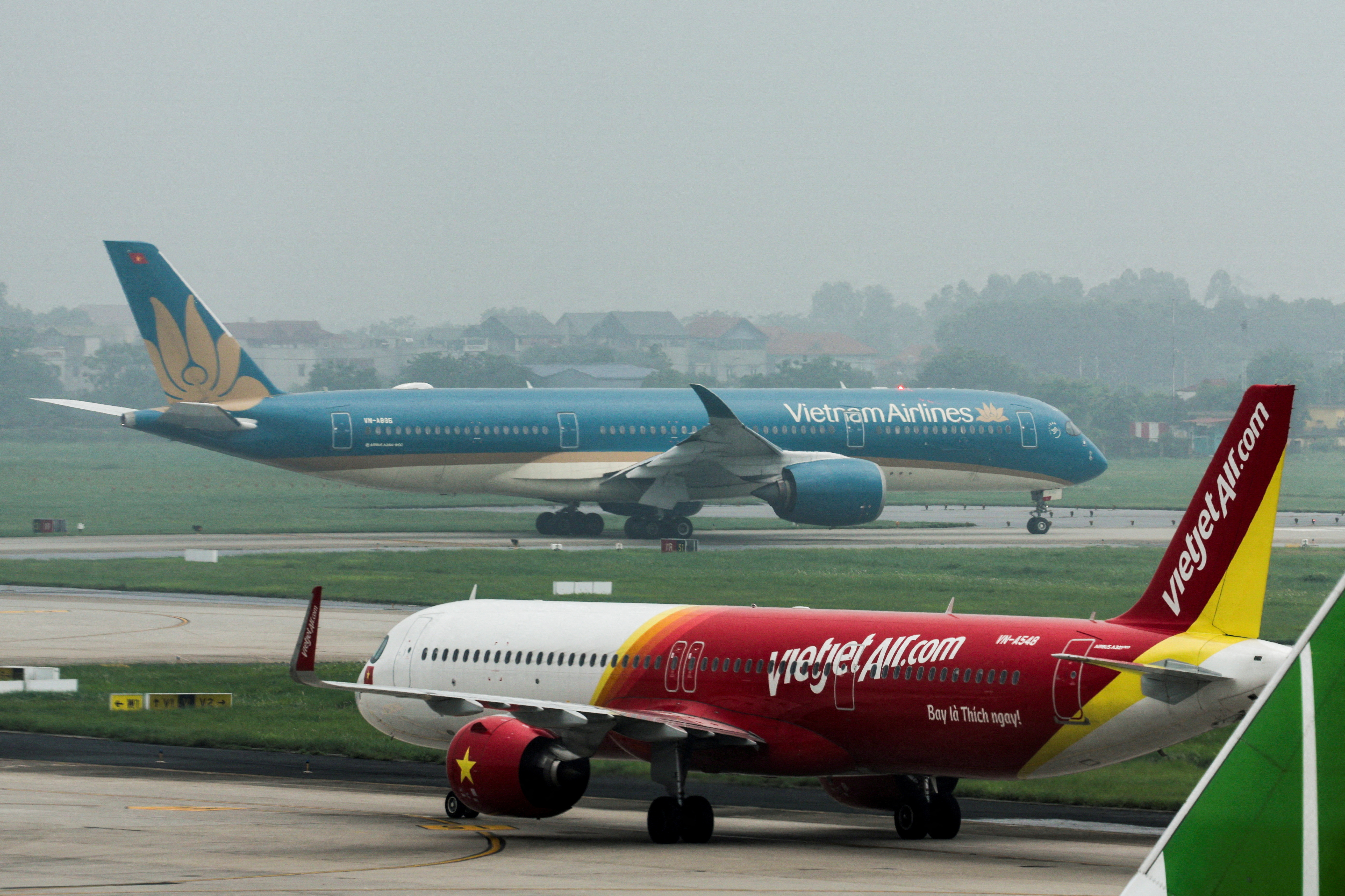 FILE PHOTO: An airplane of VietJet airline and Vietnam Airlines airplane taxi at Noi Bai International Airport in Hanoi