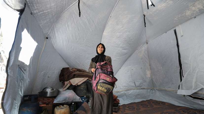 Displaced Palestinian woman Huda Junaid collects belongings inside her tent as she prepares to flee with her family after the Israeli army issued evacuation orders for a number of neighborhoods, in Jabalia in the northern Gaza Strip